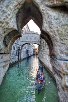 a small boat traveling down a canal under a stone arch in the middle of a city