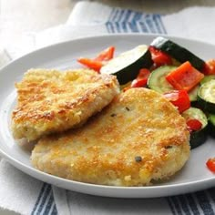 two chicken patties with vegetables on a white plate