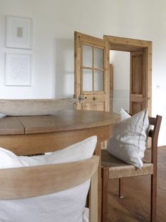 a wooden table sitting next to a white pillow on top of a chair in a living room