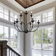 a chandelier hanging from the ceiling in a room with windows and railings