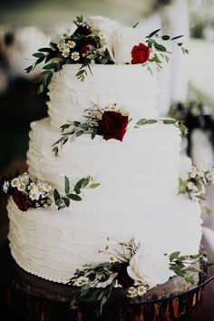 a wedding cake with white frosting and red flowers