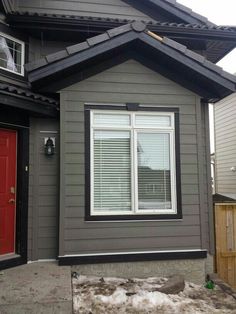 a gray house with red door and windows