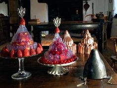 there are many different types of fruit in the glass dishes on the table, including strawberries and raspberries