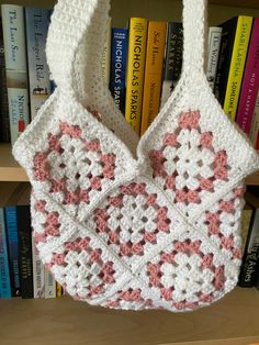 a crocheted bag hanging from a book shelf in front of a bookshelf