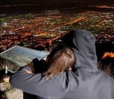 a man with long hair is looking at the city lights