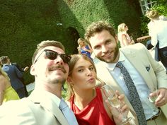 two men and a woman pose for a photo while holding wine glasses in their hands