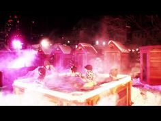 several people in a hot tub with steam coming out of the top and purple lights shining on them