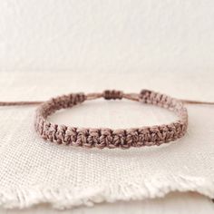 a close up of a bracelet on a white cloth with a knot at the end