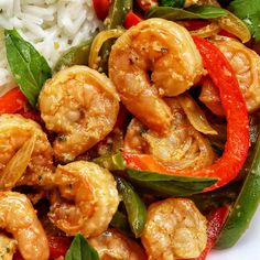 a white plate topped with shrimp and veggies covered in sauce next to rice