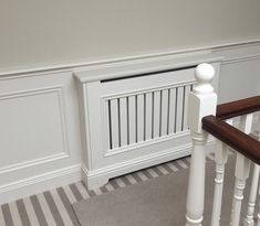 an empty room with white painted walls and wood railings, along with striped carpet