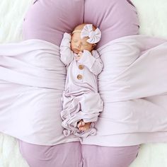 a baby is sleeping on a pillow in the shape of a flower with a bow