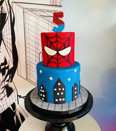 a spiderman themed cake on a table with a wall in the backgroud