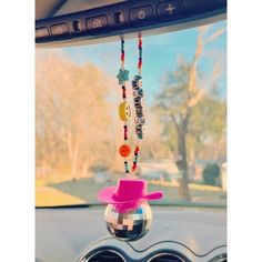 a car dashboard with a pink hat hanging from it's dash board and beads