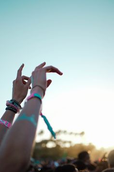 someone holding their hand up in the air at an outdoor music festival with other people