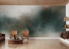 two wooden chairs sitting in front of a wall with a large painting on it's side