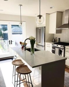 a kitchen with two stools and an island in the middle, next to a sliding glass door