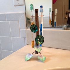 I love being greeted by art when I wake up, so why not an art toothbrush rack? The colors are in the flowers and leaves are layers of glass fired onto a copper base at 1350˚-1450˚F in multiple firings. The enameled leaves and flowers are mounted on copper wire and attached to a hardwood stick. The wood and the wires which form the toothbrush holders have been coated in polyurethane for protection and cleanliness. Finished height is 8". Flowers are 1.75" diameter. From the tip of one leaf to the Wood Toothbrush Holder, Green Toothbrush, Wood Toothbrush, Toothbrush Holders, Bath Art, I Wake Up, Flowers And Leaves, Wake Me Up, Toothbrush Holder