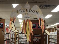 a library with several bookshelves filled with books and paper cranes hanging from the ceiling