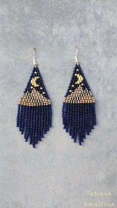 a pair of blue and white beaded earrings on top of a gray surface with the word