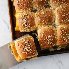 several rolls with sesame seeds on them in a baking pan