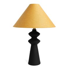 a black table lamp with a yellow shade on it's side and a white background