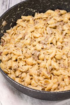 a skillet filled with macaroni and cheese sitting on top of a table