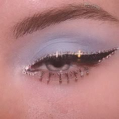 a woman's eye with silver makeup and glitters on her lashes, looking down at the camera