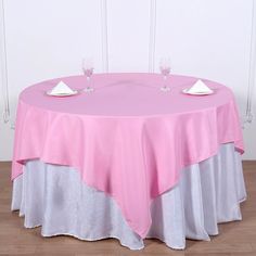 a round table with two wine glasses on it and a pink cloth over the top