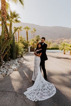 a bride and groom standing in front of palm trees