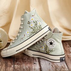 Custom Embroidered Shoes for Women, Daisy Embroidered Converse for Bride, Bridal Flowers Embroidered Sneaker for Wedding, Unique Gifts for Her 💚 Immerse yourself in the intricate craftsmanship as we lovingly hand embroider rustic flowers onto your chosen Converse pair 💚 🌿 The listed price encompasses both the Converse Shoes and the showcased Embroidery Designs. 1. MANUFACTURING PROCEDURE 🌿 Upon receiving your order, we initiate the shoe preparation process. If your chosen shoes are readily a Converse Shoes Blue, Embroidered Converse High Tops, Embroidered Vans, 1970s Shoes, Cute Converse Shoes, Embroidered Sneakers, Embroidered Converse, Cute Converse, Blue And Purple Flowers