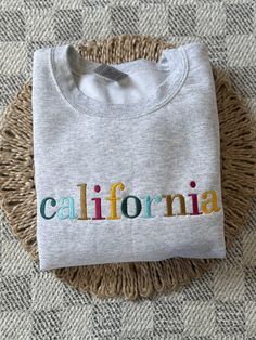 A perfect custom embroidered gift for you or any friends who love their state!  ~The Crewneck~ * Comfy Gildan 18000 sweatshirt * Fits true to size - see size guide chart in photos * For an oversized fit order 2 sizes up! * Embroidered in the USA * Embroidery stabilizer will be cut to the shape of the design ~Care~ * Machine wash cold, inside out, and with like colors  * Be mindful of the other materials you wash this item with * Tumble dry low or hang dry  * Do not iron directly on the embroider Casual T-shirt With Multicolor Embroidery And Logo, Custom Embroidered Long Sleeve T-shirt, Casual Long Sleeve T-shirt With Multicolor Embroidery, Casual Tops With Multicolor Embroidery And Logo, Casual Embroidered Multicolor Top, Embroidered Cotton Short Sleeve Sweatshirt, Cotton Tops With Multicolor Embroidery And Logo, Multicolor Crew Neck Top With Embroidered Logo, Cotton Sweatshirt With Multicolor Embroidered Text