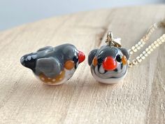 two glass birds sitting on top of a wooden table next to a chain link necklace