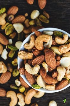 a bowl filled with nuts and pistachios on top of a wooden table