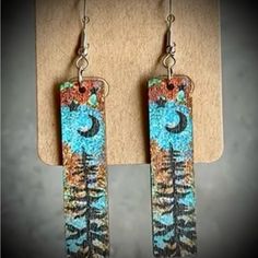 the earrings are decorated with blue and orange designs on wood planks, while hanging from metal hooks