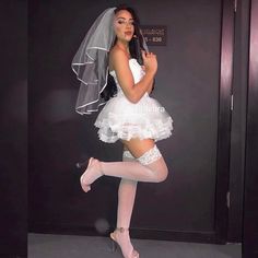 a woman in a white dress and veil posing for the camera with her legs crossed