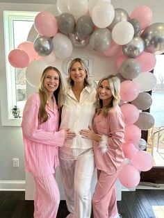 three women standing in front of a balloon arch