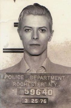 a mug shot of a man in a suit and tie holding a sign that says police department rockefeller, ny