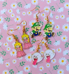 four pairs of cartoon character dangle earrings on a pink background with flowers and daisies