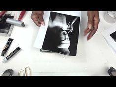 two hands are holding an open book on a table next to some scissors and other items