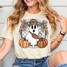 a woman wearing a t - shirt with a cartoon character holding a coffee cup and pumpkins