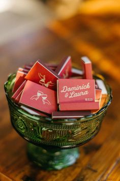 a glass bowl filled with small candy bars on top of a wooden table next to a bottle