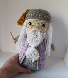 a crocheted wizard doll is holding a wand in his hand and wearing glasses