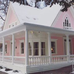 a pink and white house with snow on the ground near it's front porch