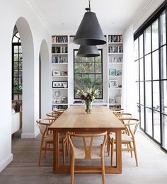 a dining room table and chairs with bookshelves in the background