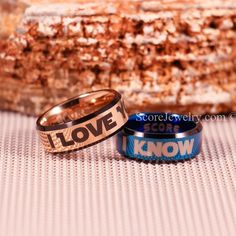 two wedding rings with the words lovey and know on them sitting next to each other