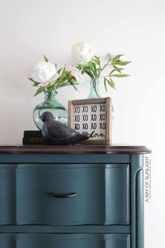 a blue dresser with flowers and an xoxo box on top