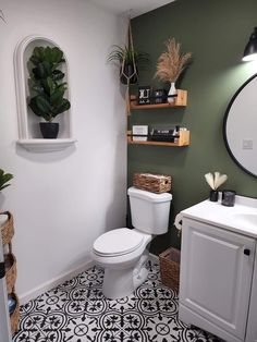 a white toilet sitting next to a sink in a bathroom under a mirror and potted plant