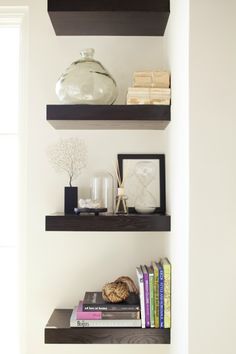 three shelves with books and vases on them