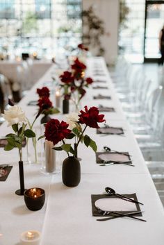 long table with white and red flowers in vases on each side, along with candles