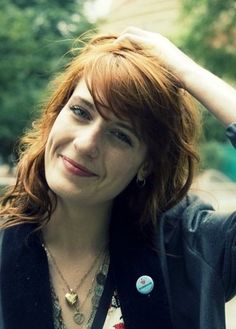 a woman with red hair wearing a black blazer and blue shirt is posing for the camera